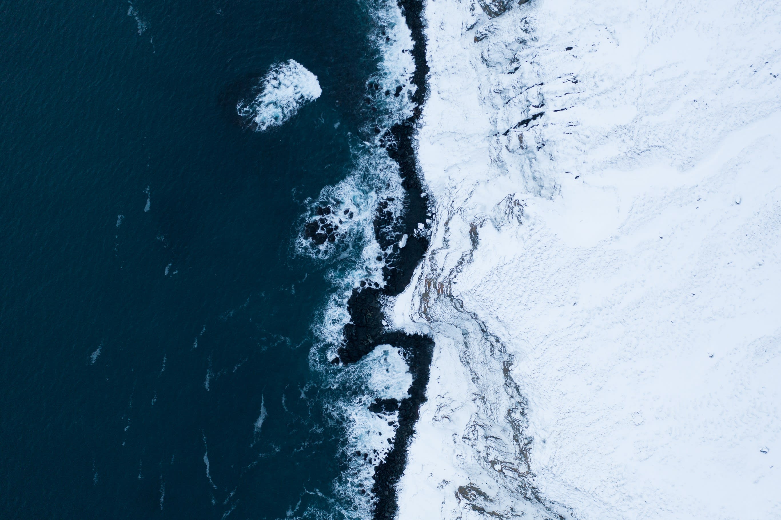 a birds eye view of the spot where a rugged mountain in Iceland meets the shore