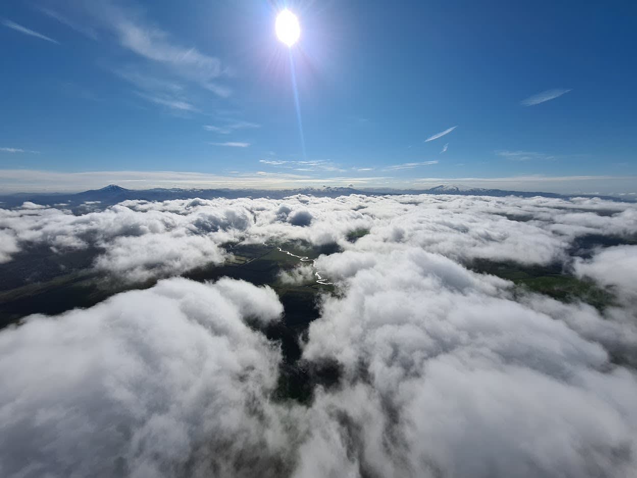 an aerial view of the landscape from the hot air balloon, with views from above the clouds and beneath to the land below