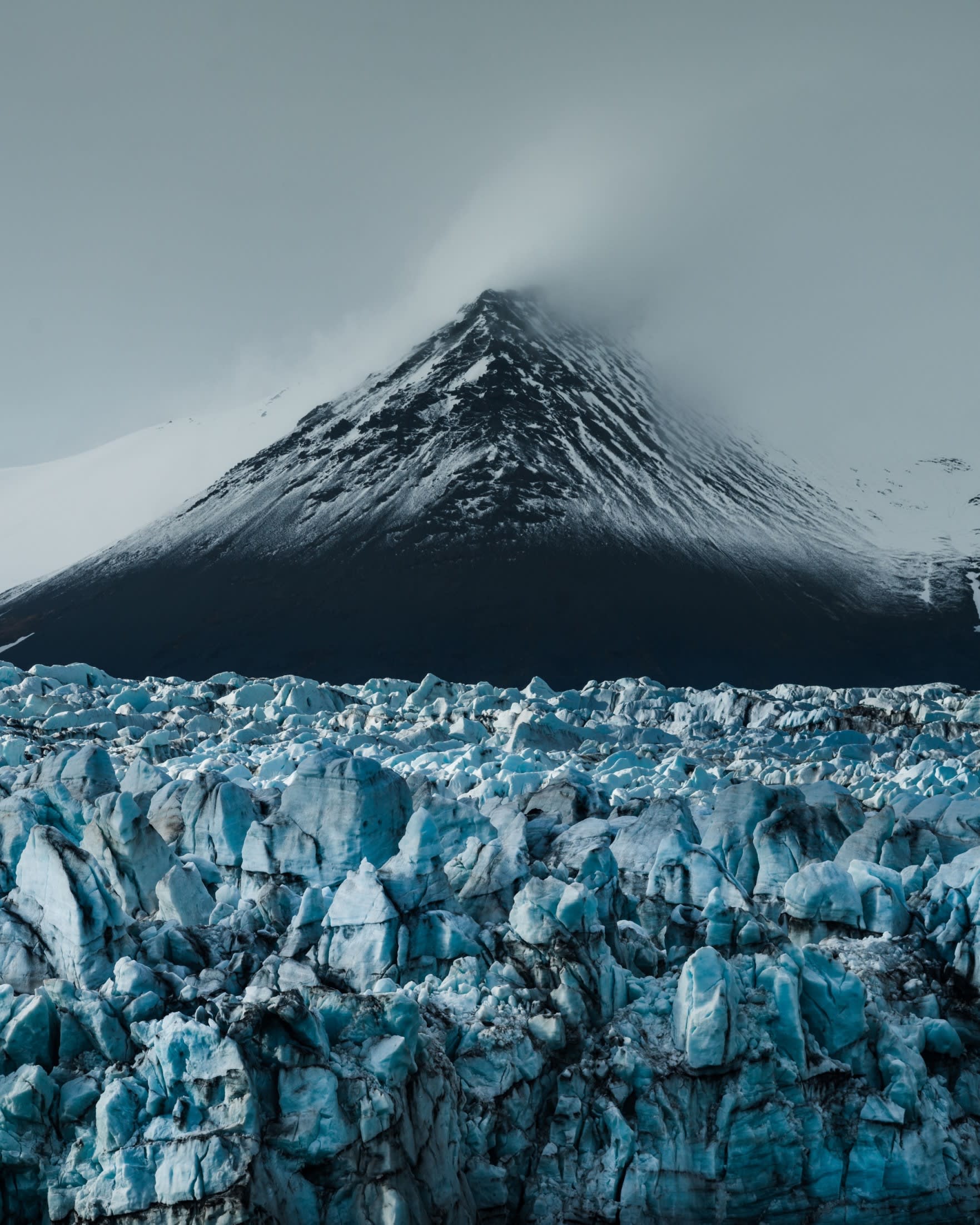 The bright blue Vatnajokull glacier in Iceland set against a snow covered mountain