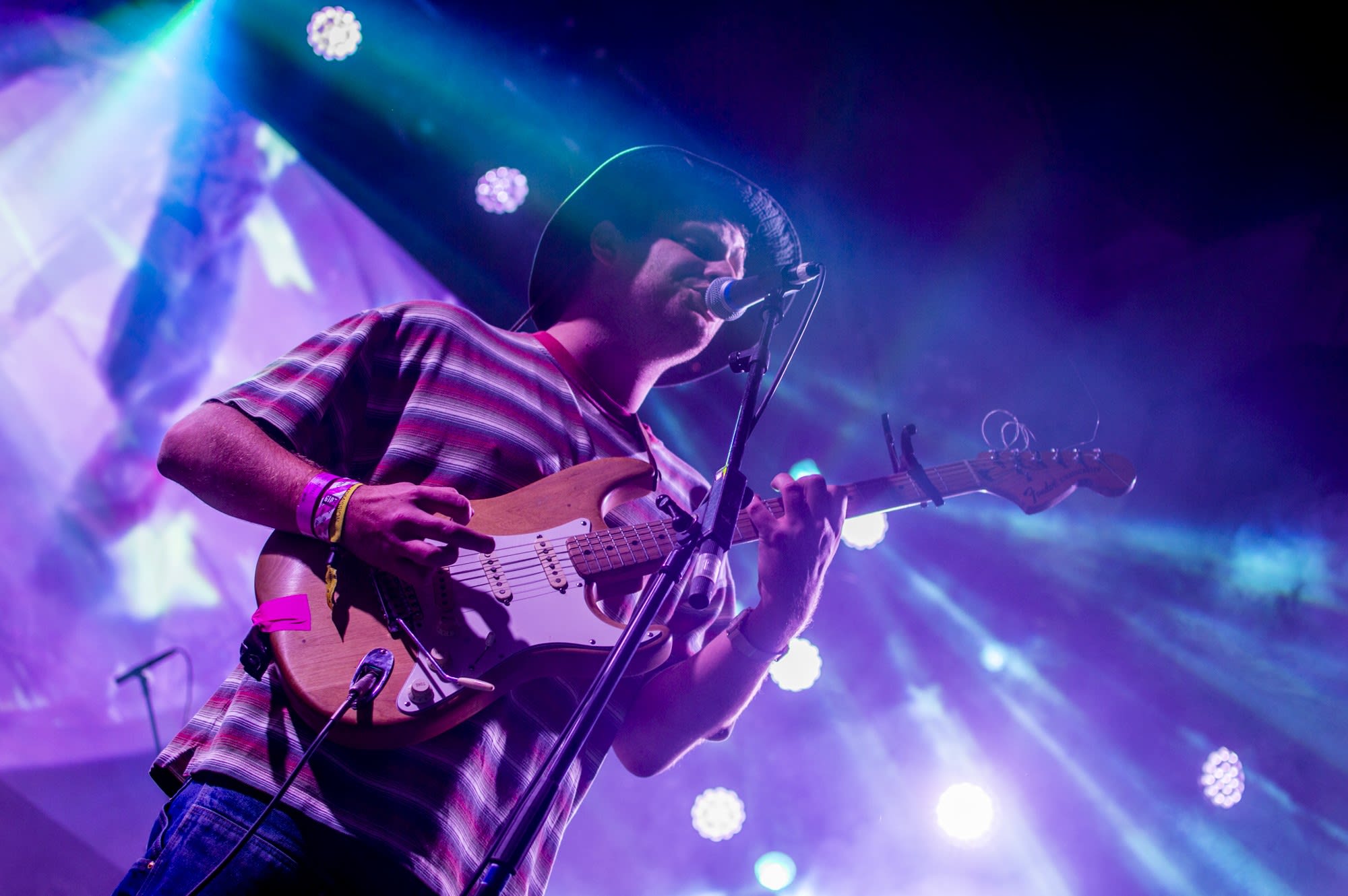 Mac Demarco performing at Iceland Airwaves 2019 with a guitar in hand and concert lights behind