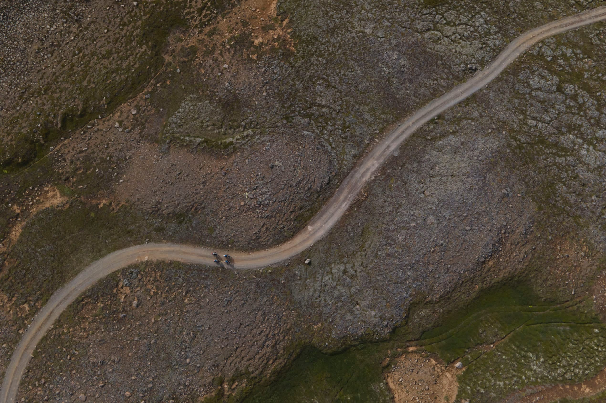 an aerial view of a road in Iceland winding through the rugged landscape