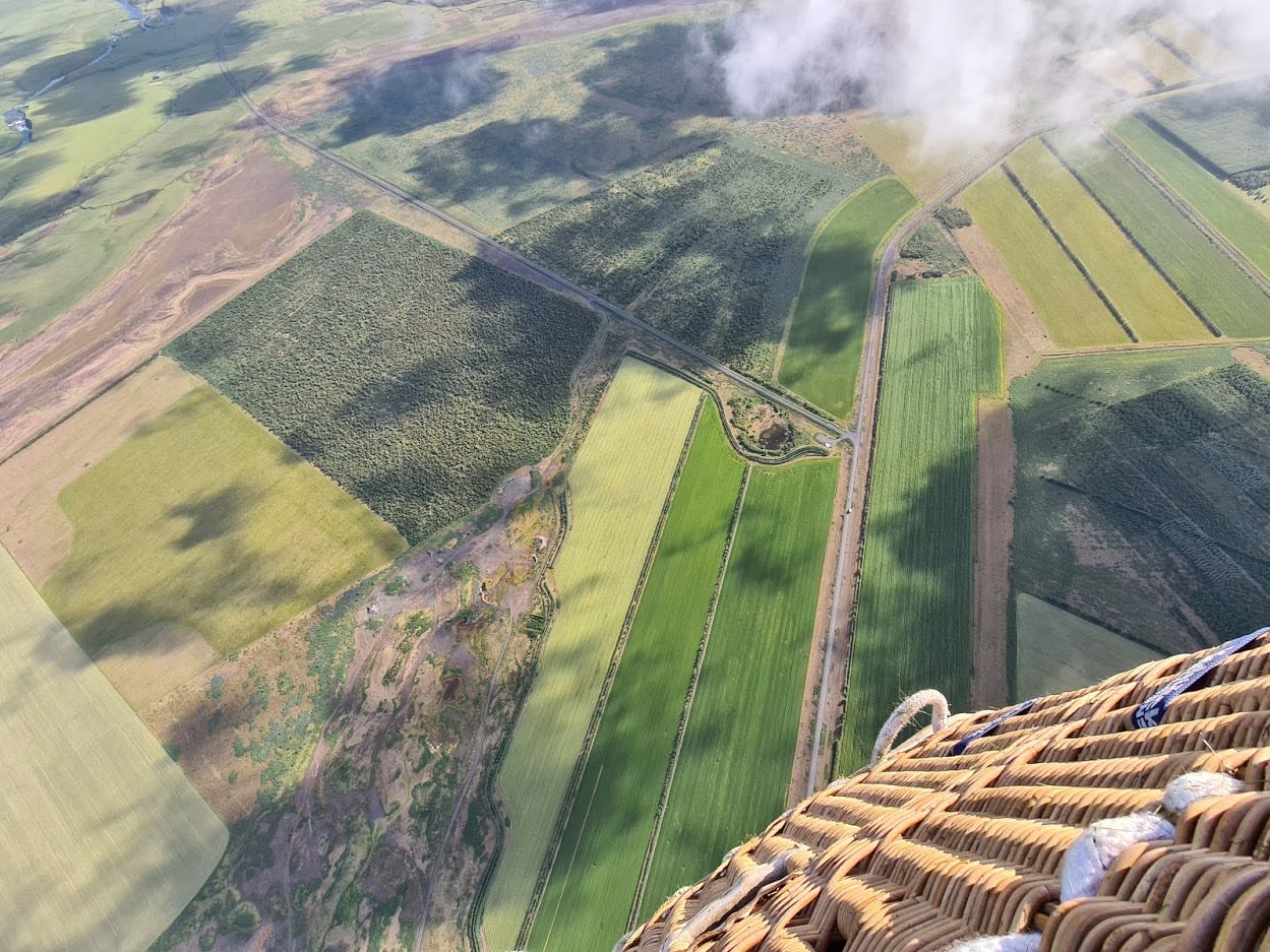 a view from within the basket, with a partial view of the basket and views looking down to the farmers fields below