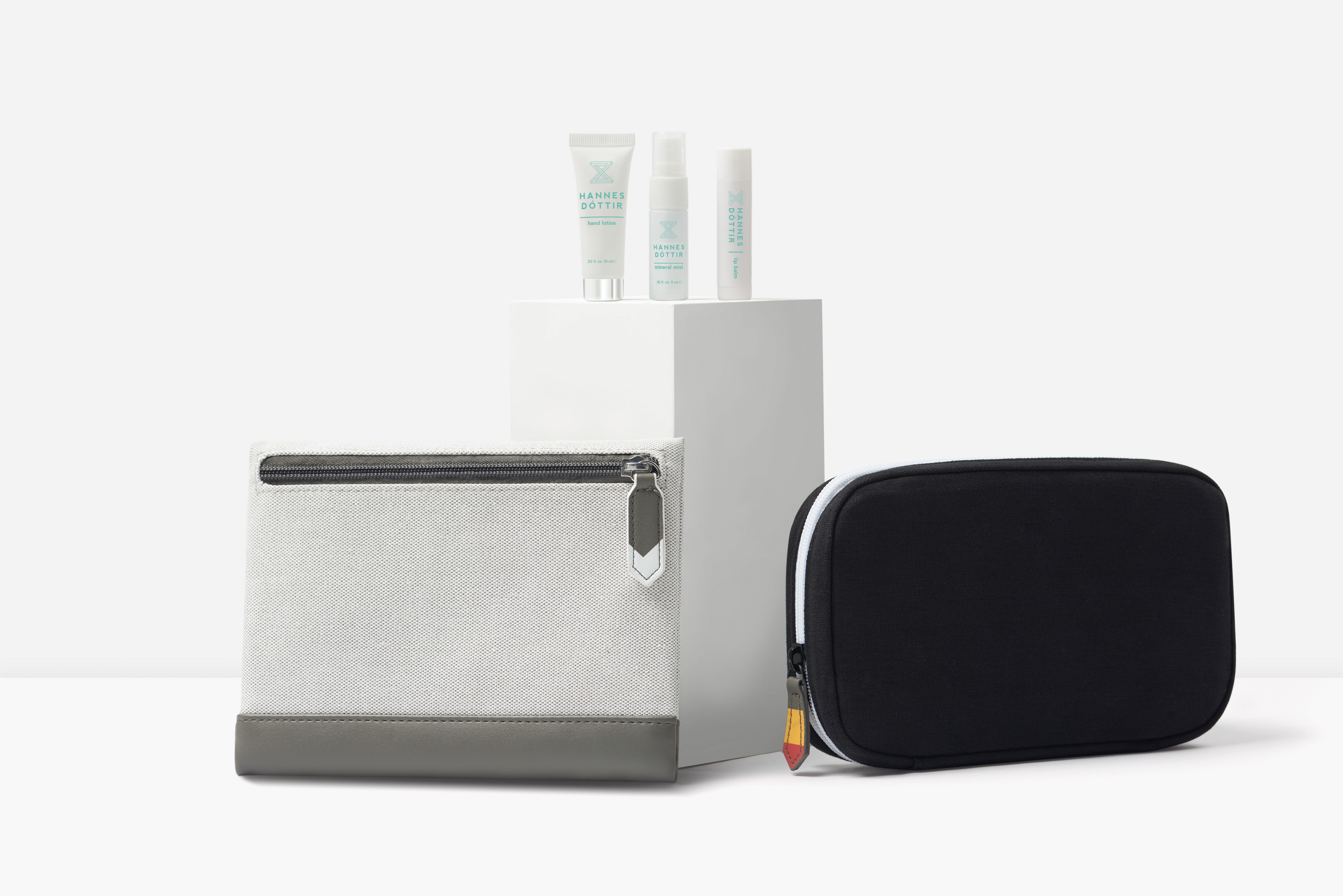 Icelandair's two new amenity designs shown side by side with some toiletries placed on a pedestal behind the bags