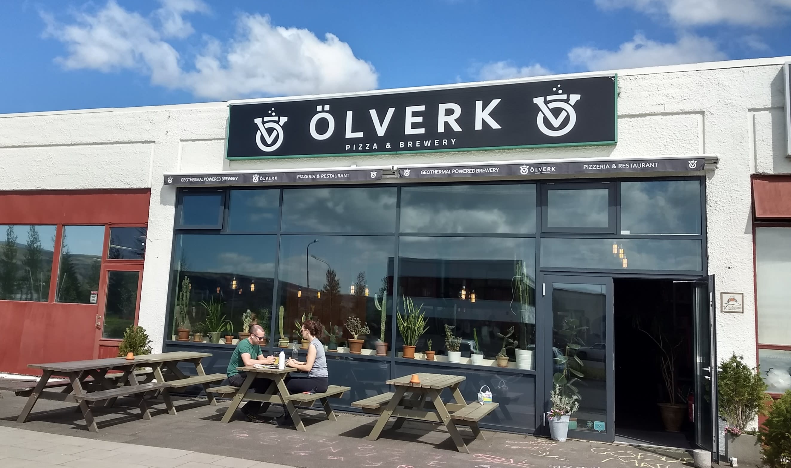 two people enjoy beer and pizza outside Olverk brewery in Hveragerdi in Iceland