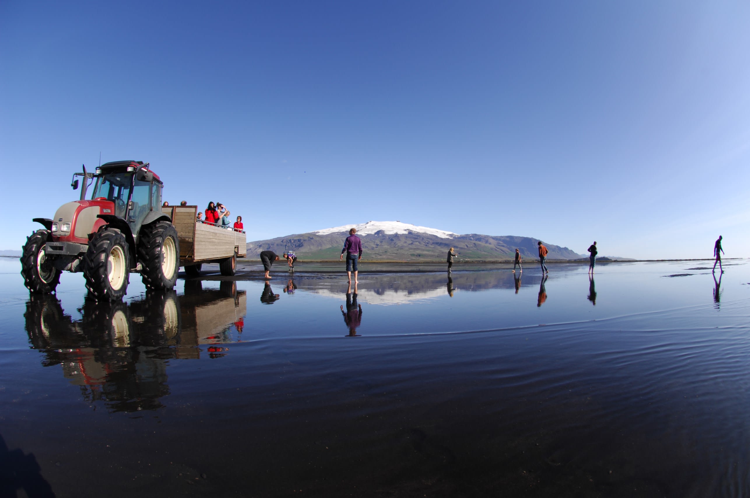 A tractor parked on a wet black sand beach on route to Ingolfshofdi