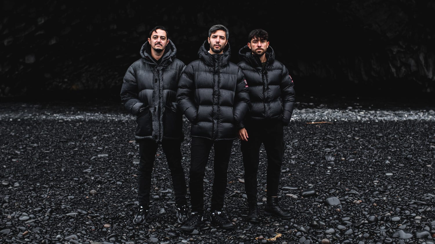 The three members of the band Meduza pictured on one of Iceland's famous black sand beaches wearing all black clothing