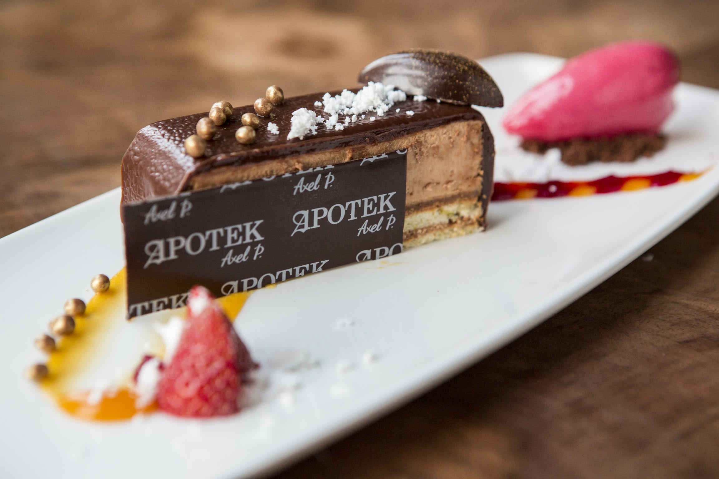 a close up of a chocolate cream cake with a chocolate decoration that reads 'Apotek'