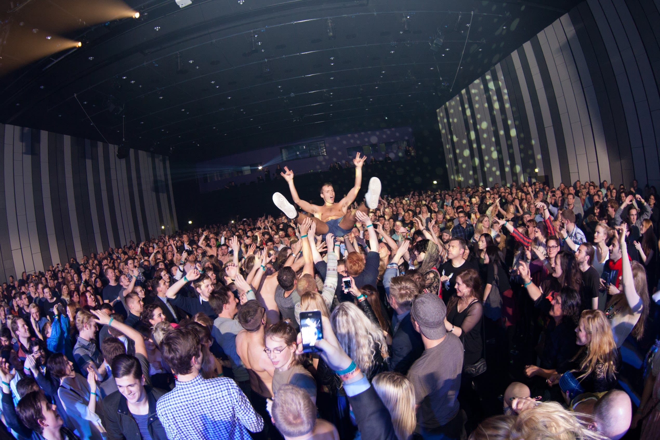 a lively crowd lifts somebody up above head and allows them to crowdsurf