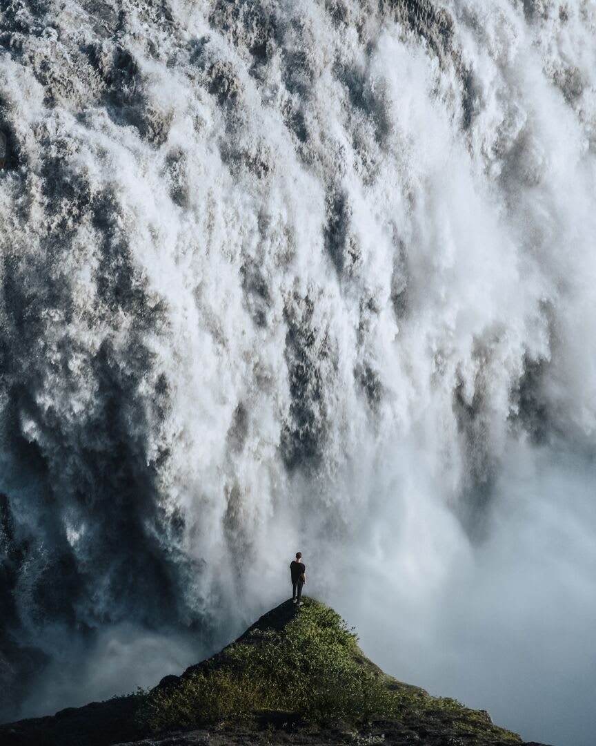 A close up image of Dettifoss waterfall with a person silhouetted in the foreground