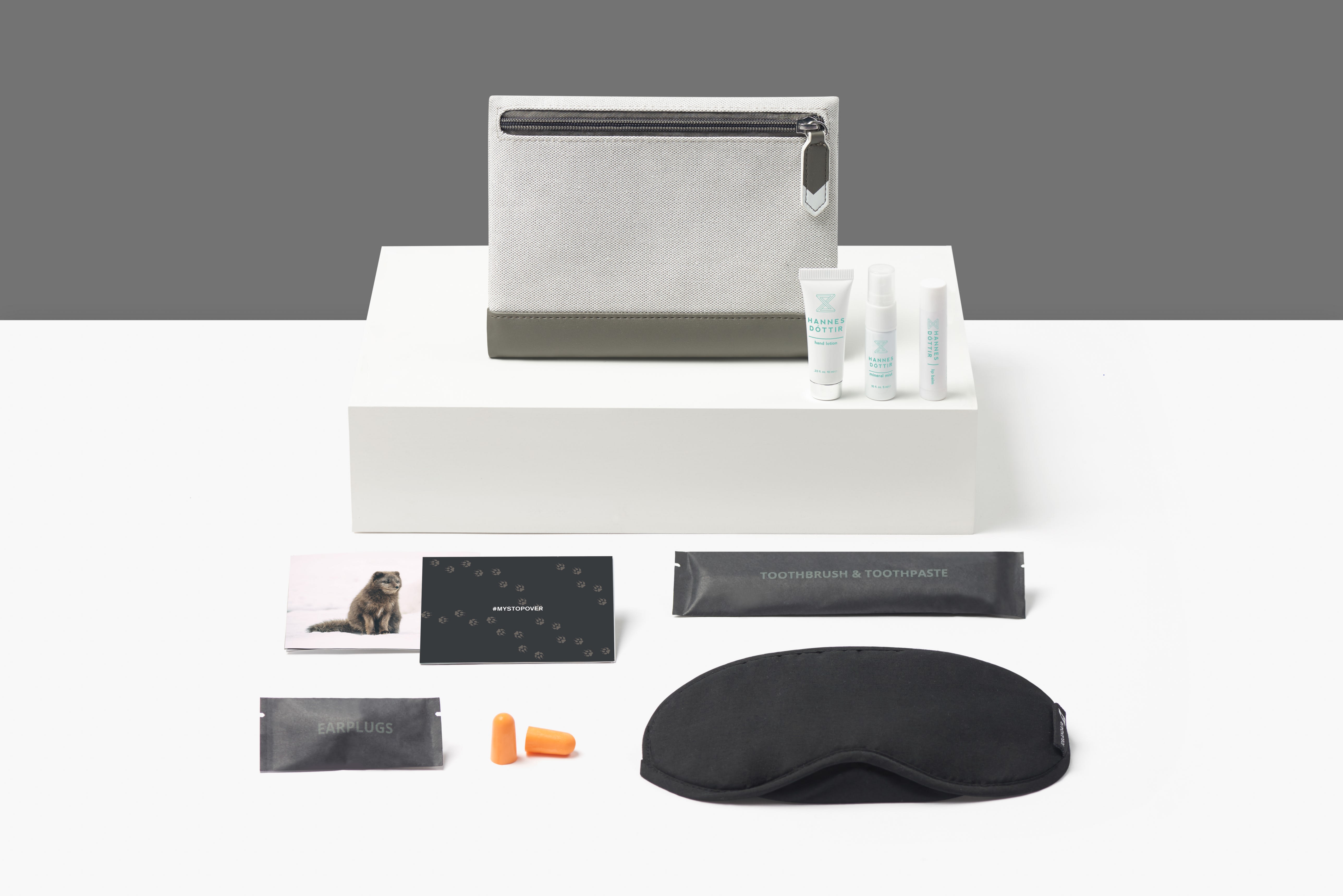 Icelandair's new amenity kit dismantled with all the items inside place neatly around it. The kit includes earbuds, eyemask, toiletries, toothbrush and a small photo card