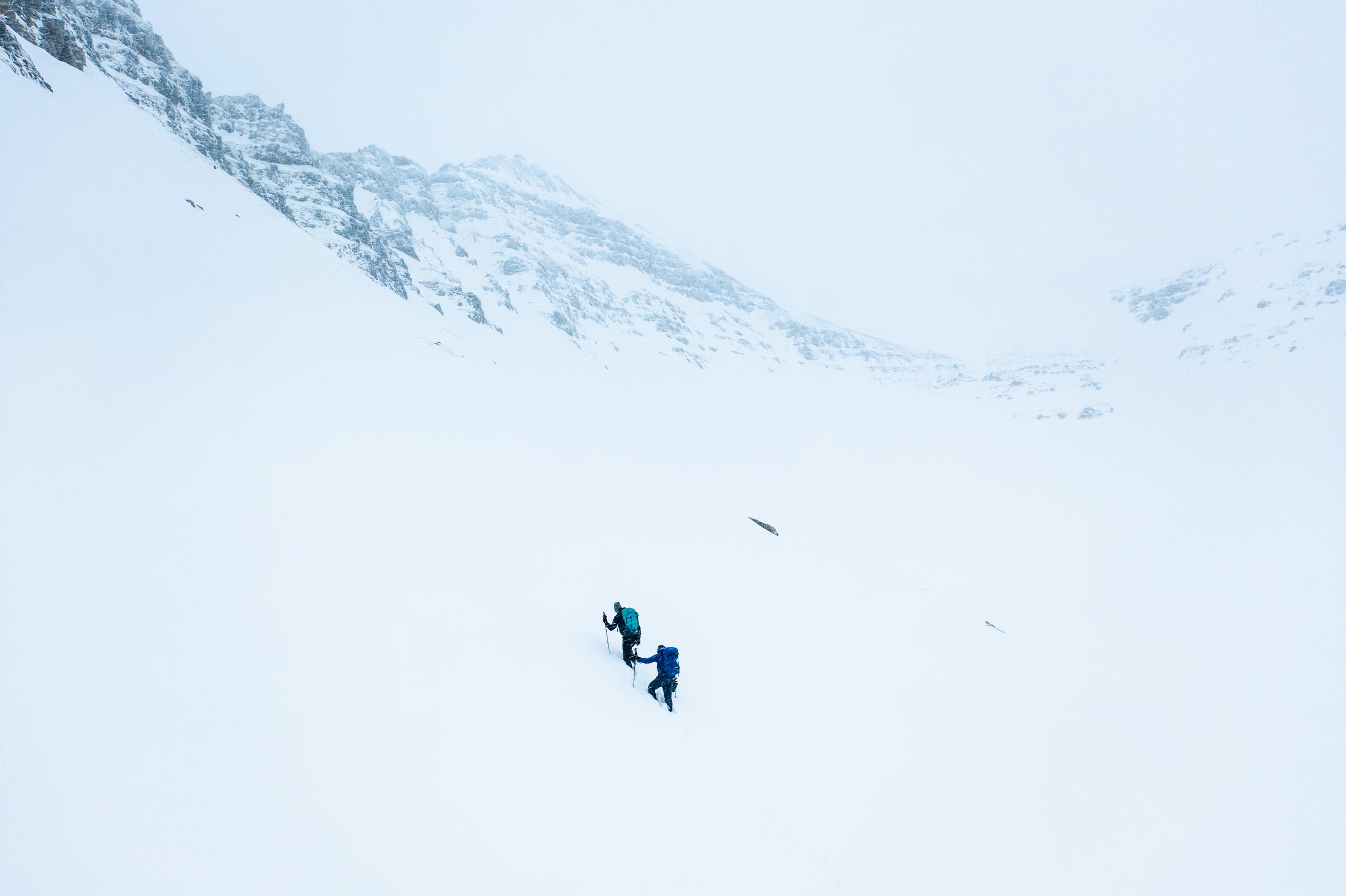 two people wearing blue and black clothing hiking through a mountaineous region in Iceland