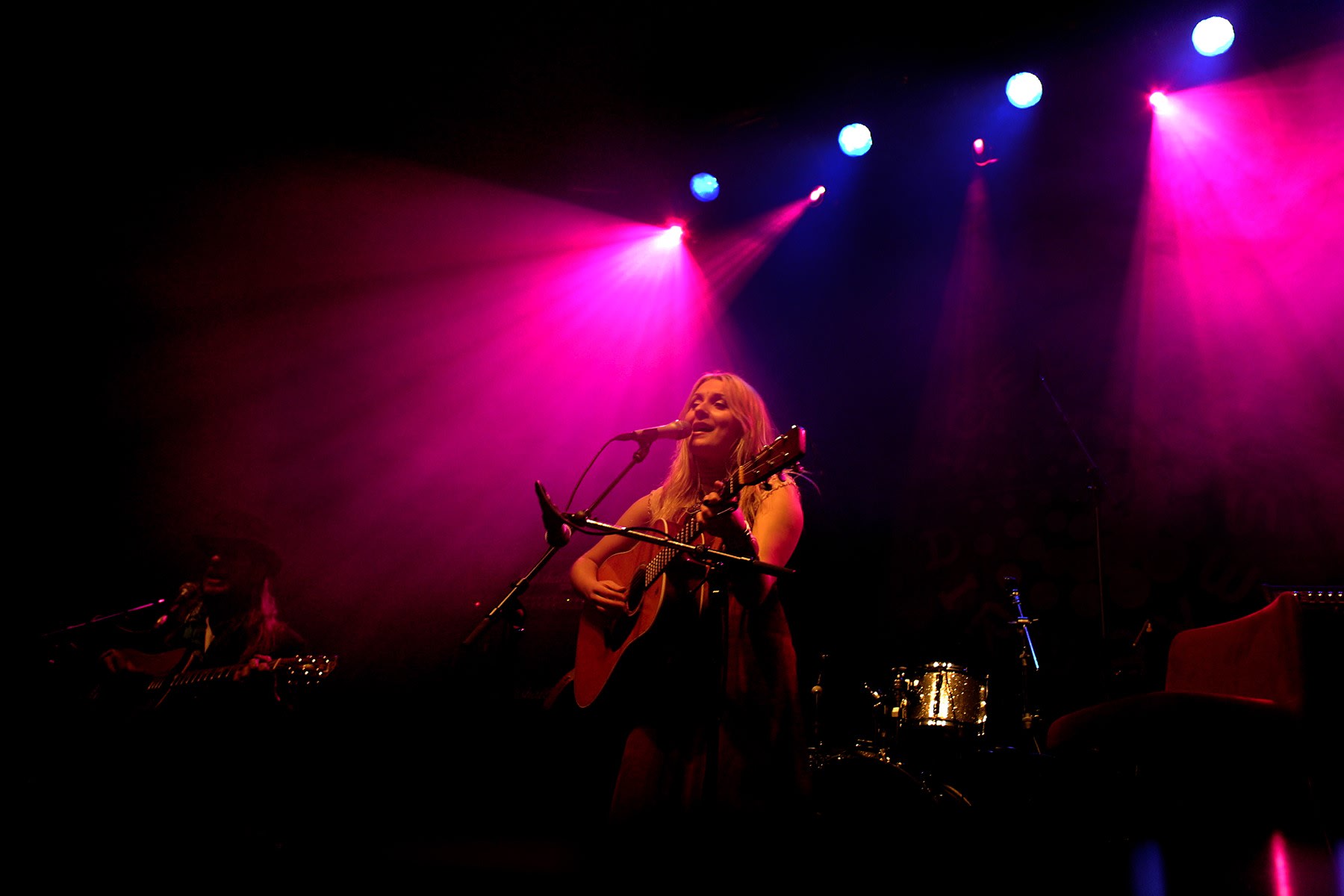 Musician Eivor pictured performing on a stage with pink lighting behind