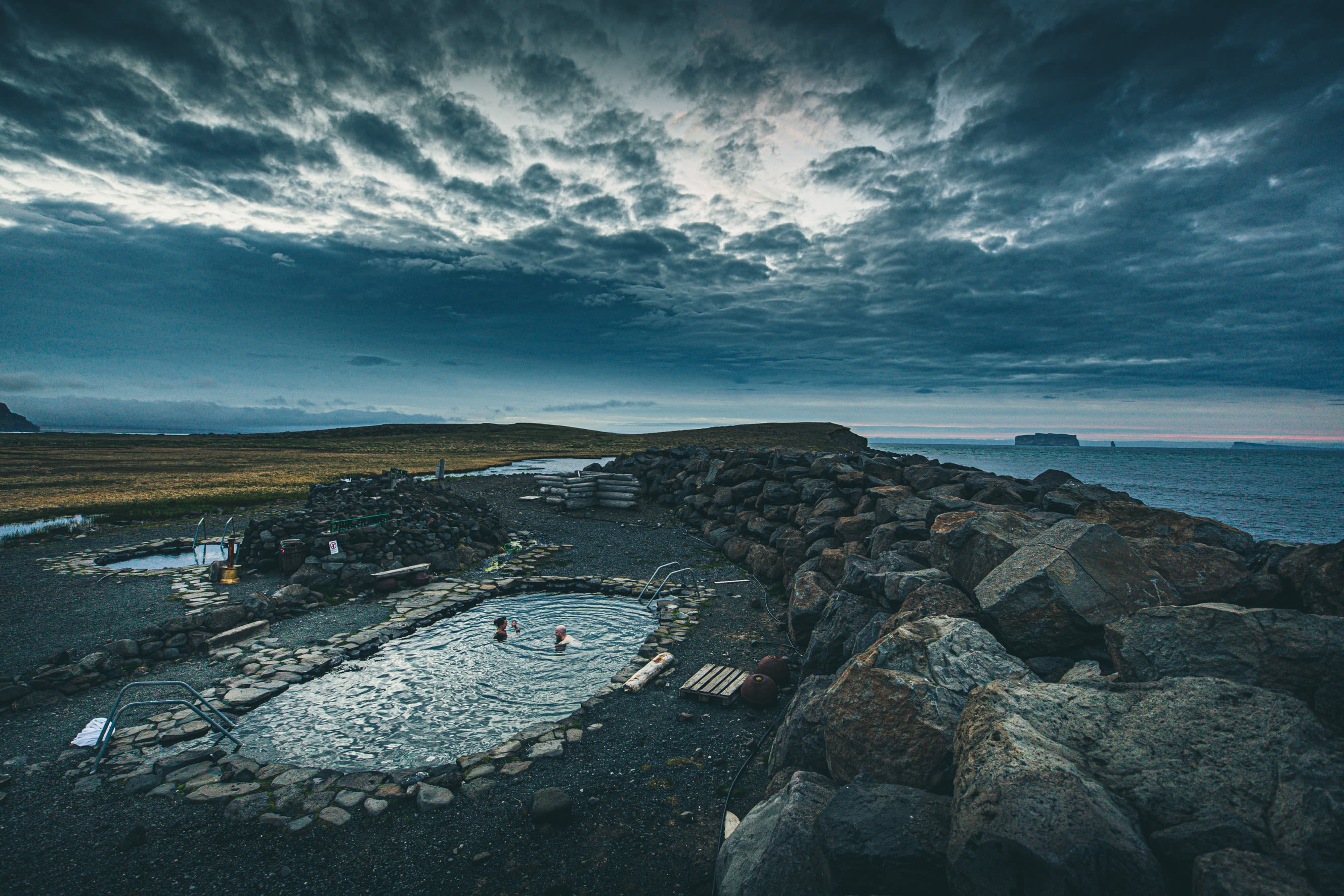 An elevated view of a small outdoor pool in Iceland with views out to sea