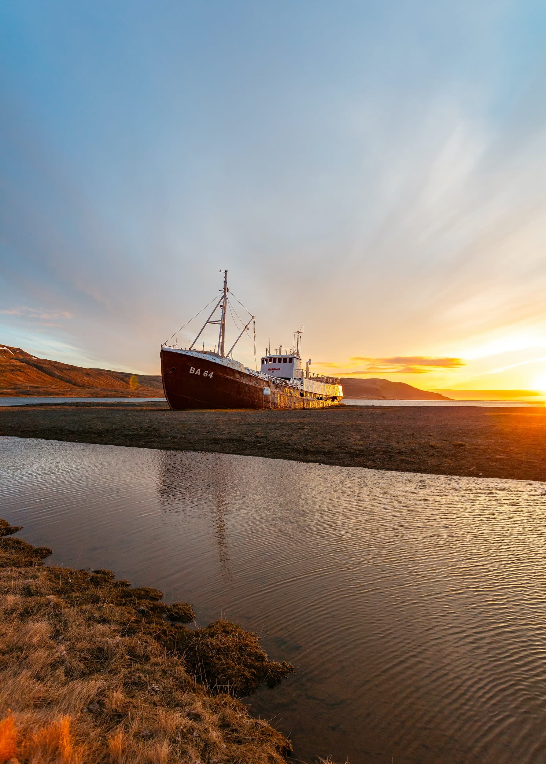 a boat - which has breached ashore in Iceland - pictured at sunset