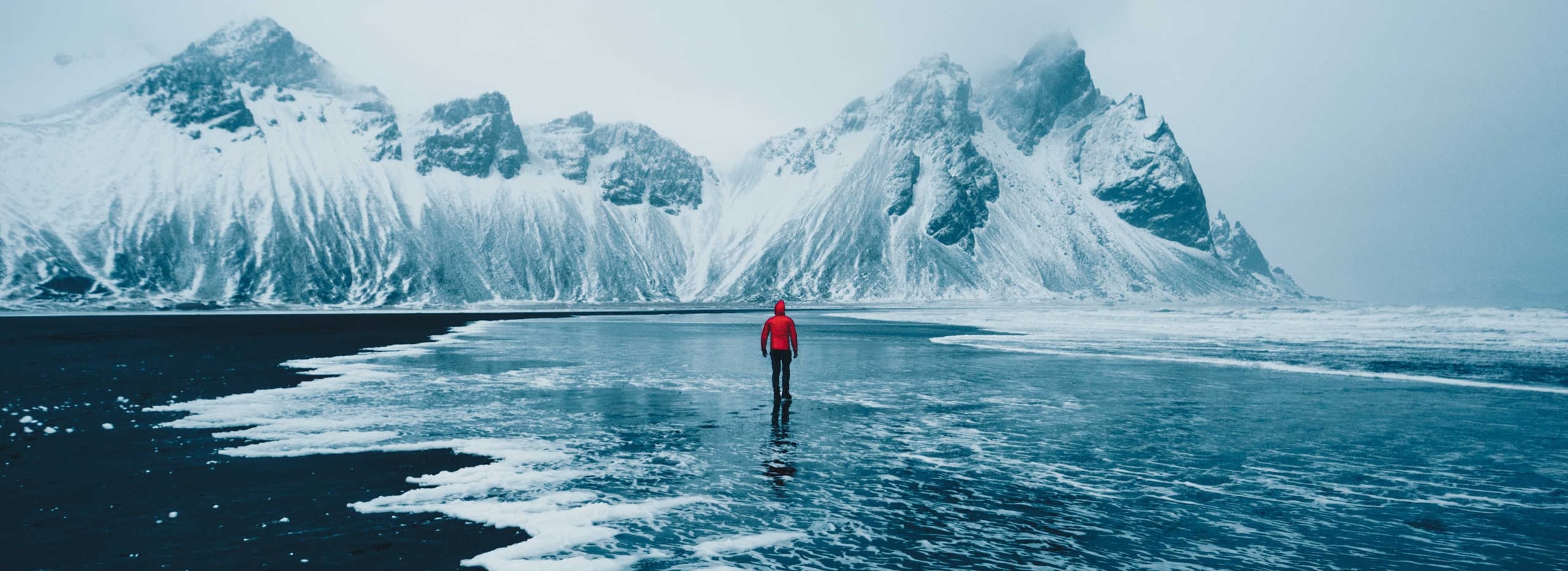 Tourist on black sand beach in Iceland winter.