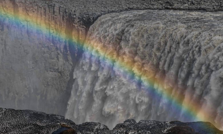 A rainbow is seen in front of the raging waters of Dettifoss waterfall