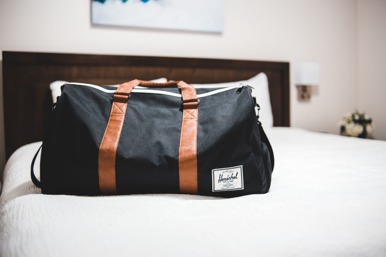 Black bag placed on top of a hotel bed